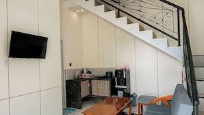 Un salon moderne avec une table basse en bois, un canapé gris et un escalier agrémenté d’une rampe décorative.