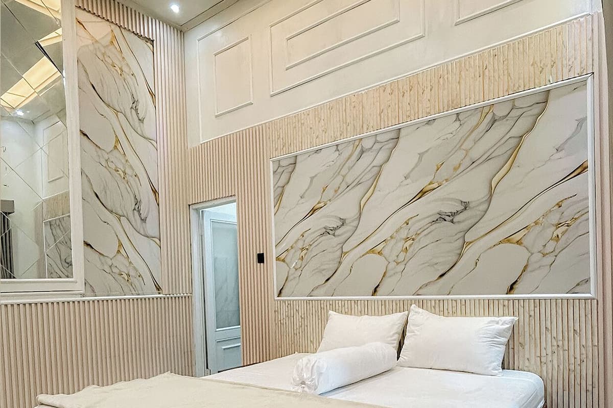A bedroom with a large bed, marble wall panels, and a mirrored closet.