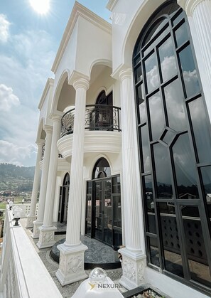 A grand building with white columns, large arched windows, and a balcony with ornate railings. - Grand House Nexura Collection (Kejajar)