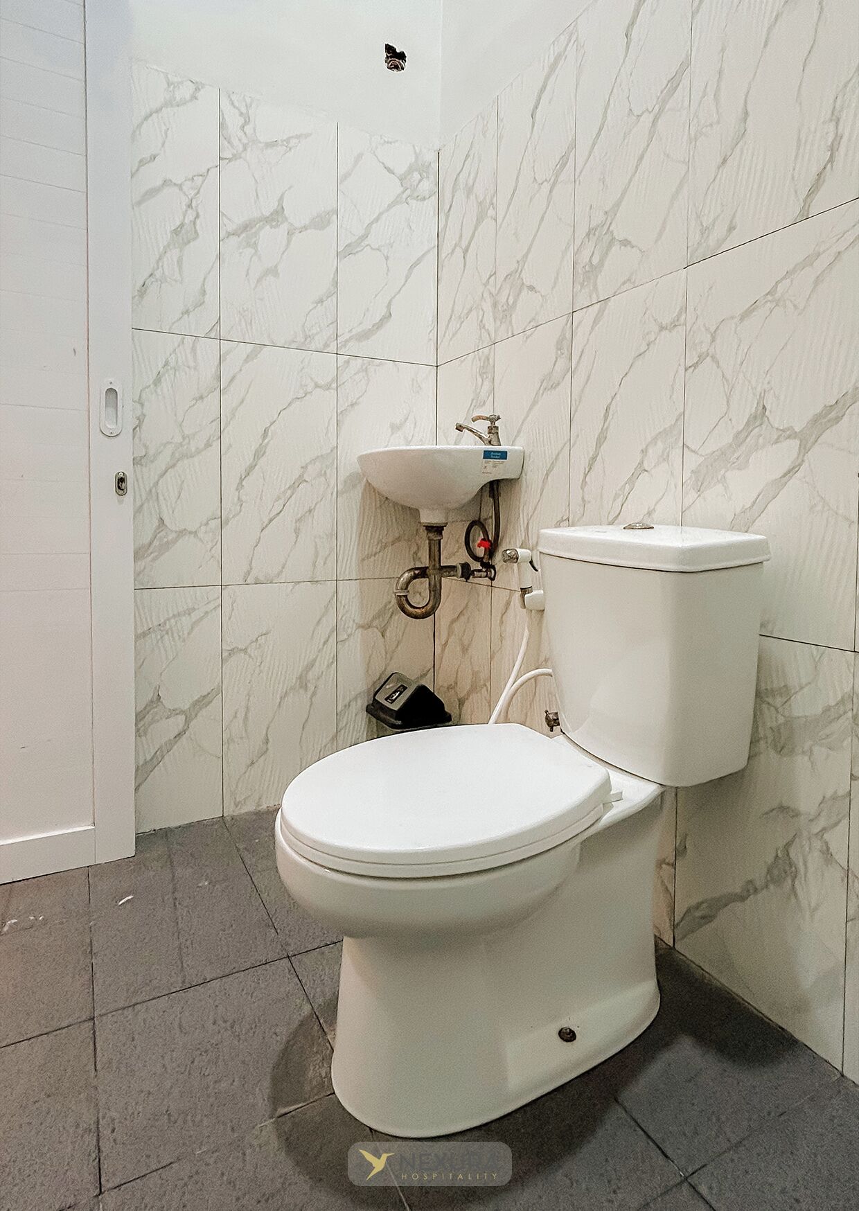 Une salle de bain avec des toilettes, un lavabo et un mur décoré d’un motif imitant le marbre.