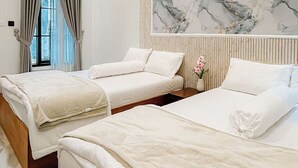 Une chambre d’hôtel avec deux lits, une grande œuvre d’art en marbre accrochée au mur et une fenêtre avec des rideaux.