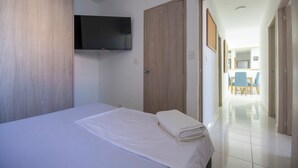 Ett hotellrum med en säng, en tv som är monterad på väggen och en garderob i trä.