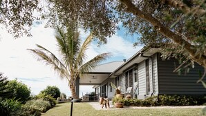 A house with a covered porch, a lawn, and a palm tree. - Potager House (Carool)