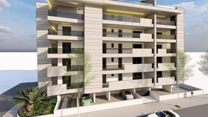 Um edifício residencial moderno de vários andares, com varandas, terraço no telhado e área ajardinada com plantas.