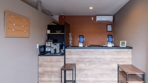 A reception area with a corkboard, a coffee machine, and a counter with a digital display. - HOTEL R9 The Yard Tagawakawara (Kawara)