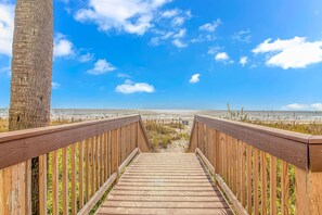 A wooden boardwalk leading to a beach with a clear sky. - Bay Watch 1101 (North Myrtle Beach)