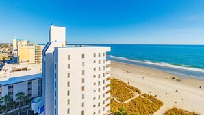 A high-rise hotel with a beach view, a sandy beach, and a clear blue sky. - Bay Watch 1101 (North Myrtle Beach)