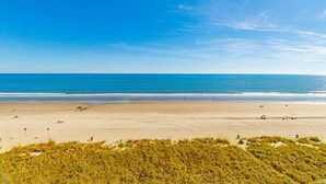 Een strand met zand, enkele mensen en een heldere lucht.