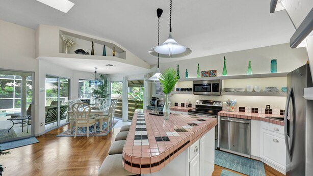 Une cuisine spacieuse dotée d’un îlot central aux lignes courbes, d’appareils électroménagers modernes et offrant une vue sur l’extérieur.
