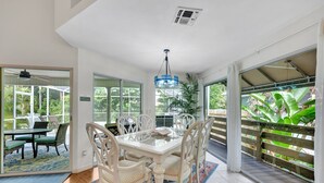 Un coin repas avec une table en verre, des chaises blanches et un luminaire suspendu bleu.