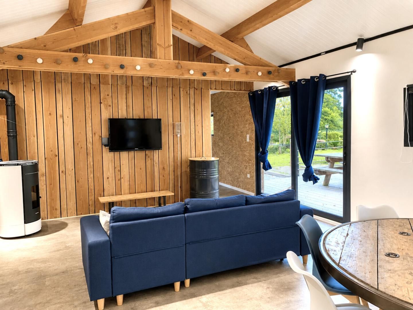 A modern living room with a blue sofa, a television, and a large window with curtains.
