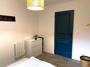A bedroom with a white dresser, a blue door, a radiator, and a hanging plant. - AT MATHILDE AND SÉBASTIEN'S (RUBIGNY)