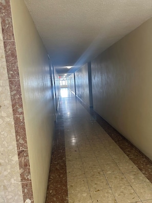 A corridor with tiled flooring and walls, leading to a bright area at the end. - Beachfront King Suite • Pool • Parking• Walk2Eat (Carolina)