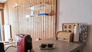 Eine Küchenarbeitsplatte mit einer Kaffeemaschine, zwei Tassen und einem Wanddekor.