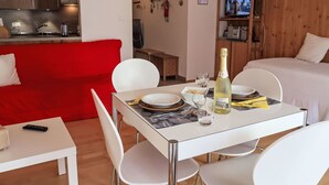 Ein modernes Hotelzimmer mit Essbereich, einem roten Sofa, einem Fernseher und einer Holzwand.