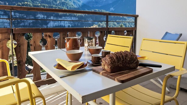 Ein Balkon mit Frühstückstisch, mit Blick auf eine Berglandschaft.