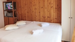 Ein Schlafzimmer mit einer Wandpaneele aus Holz, einem Bett mit weißer Bettwäsche, zwei Kissen und einem zusammengerollten Handtuch.