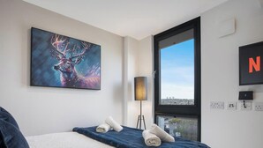 A hotel room with a bed, a painting of a deer, a TV, and a view of the city. - The Point 902 - Grampian Lettings (Aberdeen)