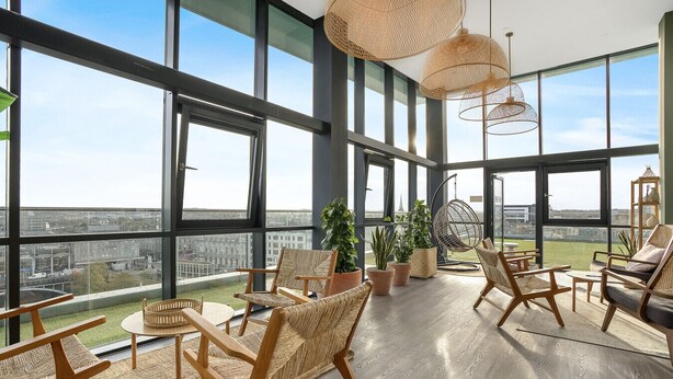 A spacious balcony with large windows, wicker furniture, and potted plants. - The Point 902 - Grampian Lettings (Aberdeen)