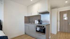 Una kitchenette compacta con horno integrado, cafetera y microondas.