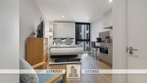 A compact bedroom with a bed, bedside table, and a small kitchenette. - The Point 922 - Grampian Lettings (Aberdeen)