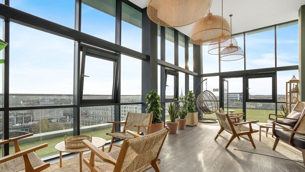 A spacious balcony with large windows, wicker furniture, and potted plants. - The Point 925 - Grampian Lettings (Aberdeen)