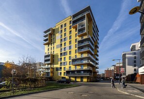 Ein mehrstöckiges Wohngebäude mit Balkonen, einer gepflasterten Straße und blauem Himmel.