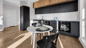 Una cucina moderna con mobili neri, un piano di lavoro bianco e un'area pranzo con un tavolo rotondo e sedie.