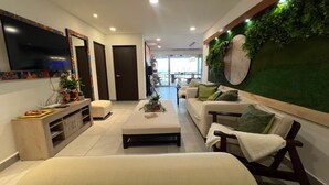 A modern living room with a sofa set, a coffee table, and a TV mounted on the wall.