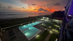 A rooftop pool area with a view of the beach and sunset.