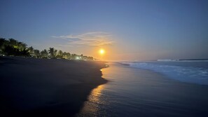 A beach at sunset with a calm sea and palm trees. - beach front/Costa del Sol/ STUNNINGVIEWS/4beds/3.5Baths/New Pool/Exquisite decor (San Pedro masahuat)