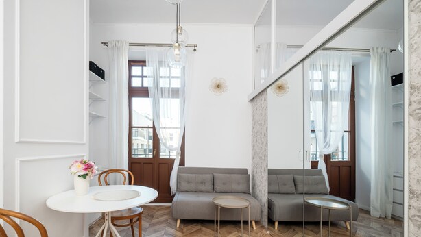 A modern living room with a sofa, a dining table with chairs, and a herringbone-patterned floor. - Nawrot Modern Apartment (Łódź)