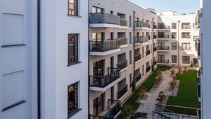 A multi-story residential building with balconies, a courtyard with greenery, and a clear sky. - Nawrot Modern Apartment (Łódź)