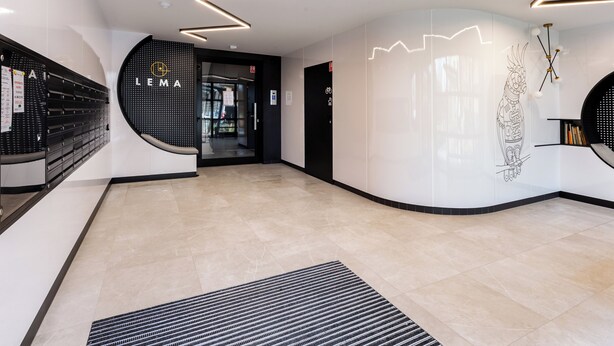 Et moderne receptionsområde med sort-hvid farvesammensætning, en digital skærm og uhindret udsigt til indgangen.