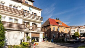 Un carrer residencial amb edificis d'altes plantes, incloent-hi una casa amb teulada vermella i un edifici blanc amb balcons.