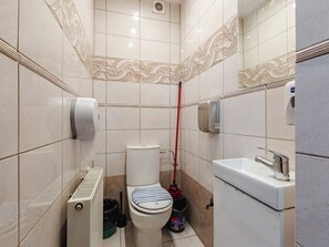 A small bathroom with a toilet, bidet, radiator, and hand dryer. - Płowce 62 Guest Spot 1P3 (Gdańsk)