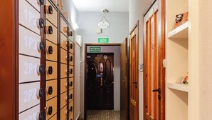 Passadís d'hotel amb diversos armaris a l'esquerra, una porta amb la inscripció 'EXIT' a la part superior i una porta de fusta a la dreta.