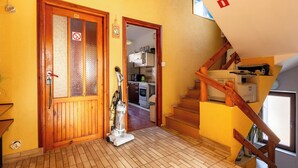 Unes escales de fusta amb barana que condueixen a un pis superior. Hi ha un aspirador al terra, a prop d'una porta amb un panell de vidre mossegat.