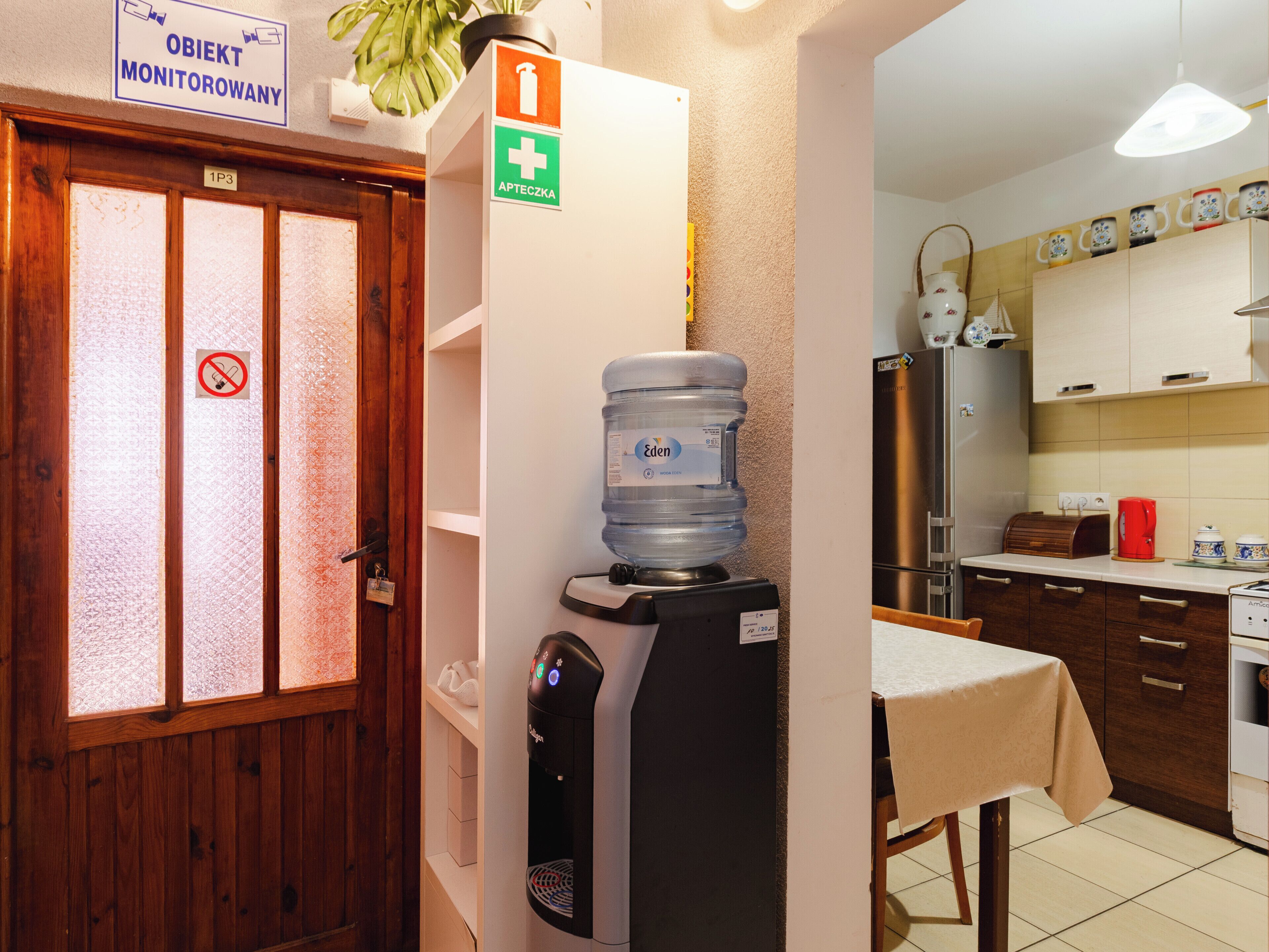 Una cuineta amb un dispensador d'aigua, una cafetera i un refrigerador.