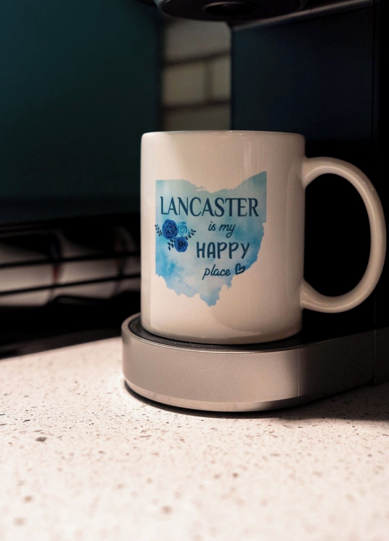 A white mug with the text "Lancaster is my happy place" on a coaster.