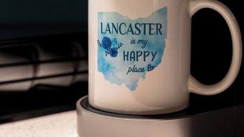 A white mug with the text "Lancaster is my happy place" on a coaster.