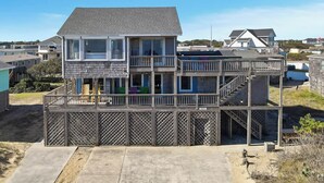 A two-story house with a balcony and a staircase leading to the upper floor. - Babe's Place | 105 ft to the beach | Dog Friendly (Kill Devil Hills)