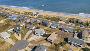 An aerial view of a coastal residential area with houses, a beach, and a road. - Babe's Place | 105 ft to the beach | Dog Friendly (Kill Devil Hills)