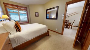 Une chambre à coucher avec un lit, une fenêtre donnant sur un beau paysage, un miroir et une porte qui mène à un coin repas.