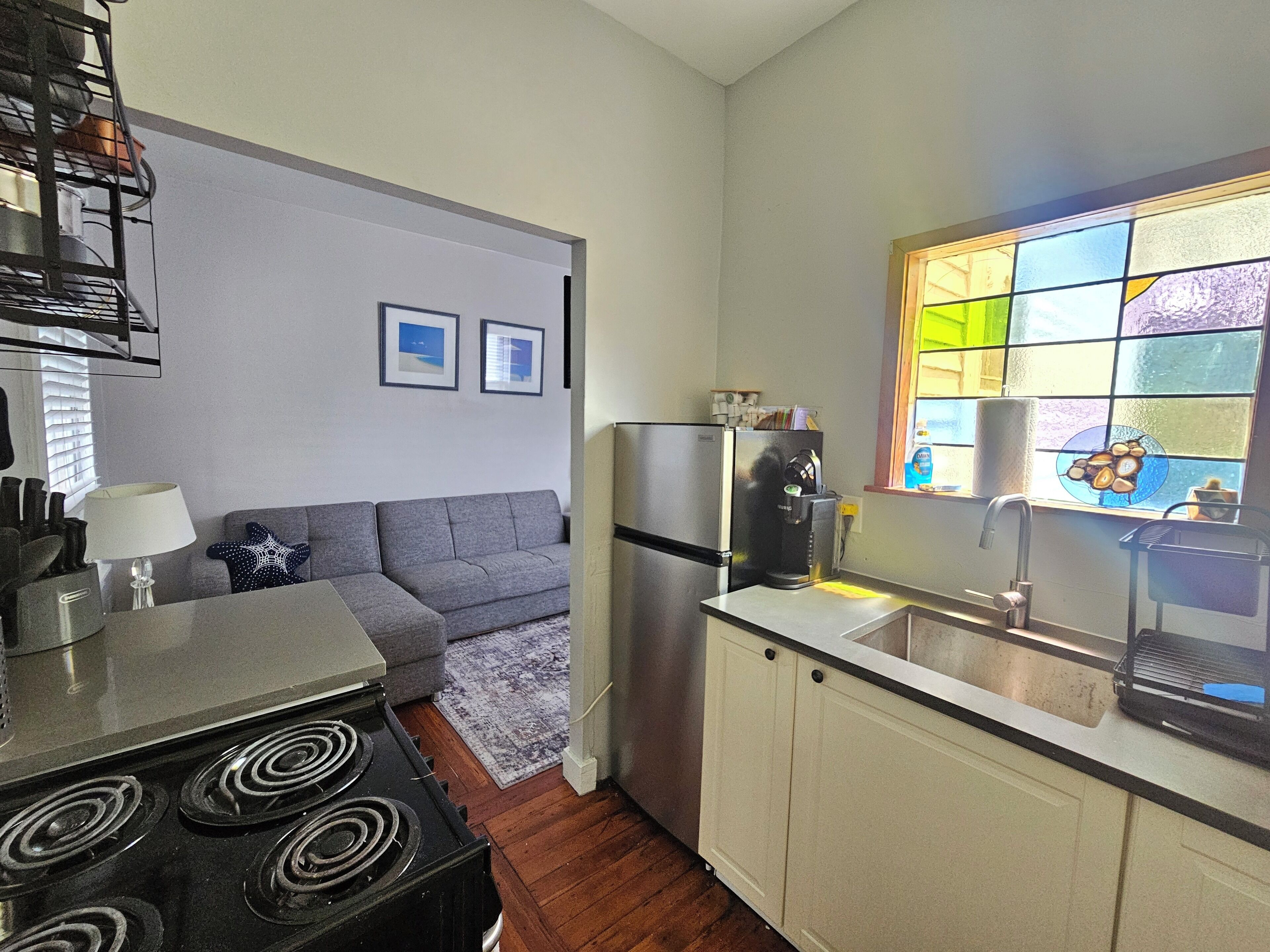 Cocina compacta con estufa, refrigerador y una ventana con vidrieras.