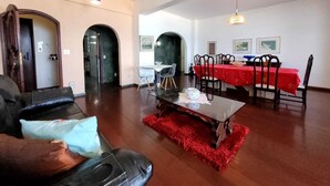 A living room with a sofa, a coffee table, and a dining area with a table and chairs. There are two doors leading to other rooms. - Copacabana Oceanfront • 3 Spacious Bedrooms • Incredible Ocean View (Rio de Janeiro)