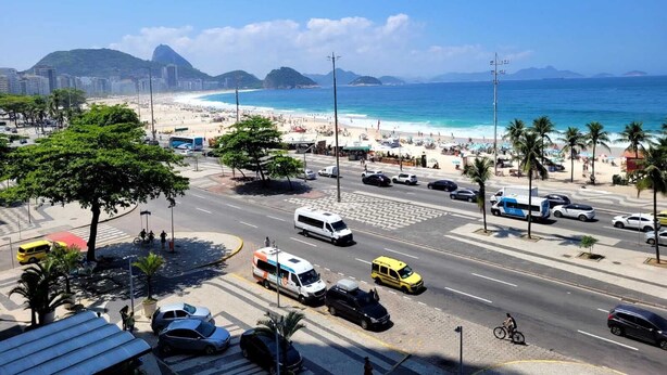 A coastal cityscape with a beach, vehicles, and a clear sky. - Copacabana Oceanfront • 3 Spacious Bedrooms • Incredible Ocean View (Rio de Janeiro)