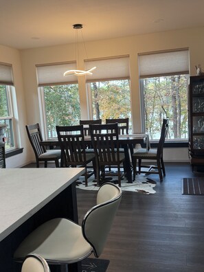 A dining area with a table and chairs, large windows with blinds, a ceiling light fixture, and a cowhide rug on the floor. - Welcoming 3-bedroom house with AC in Holly Lake Ranch (Holly Lake Ranch)
