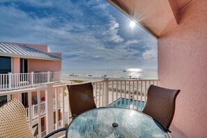 A balcony with a view of the ocean, a pool, and a table with chairs. - Beach Front Bliss at Anna Maria Island Club 40 (Bradenton Beach)