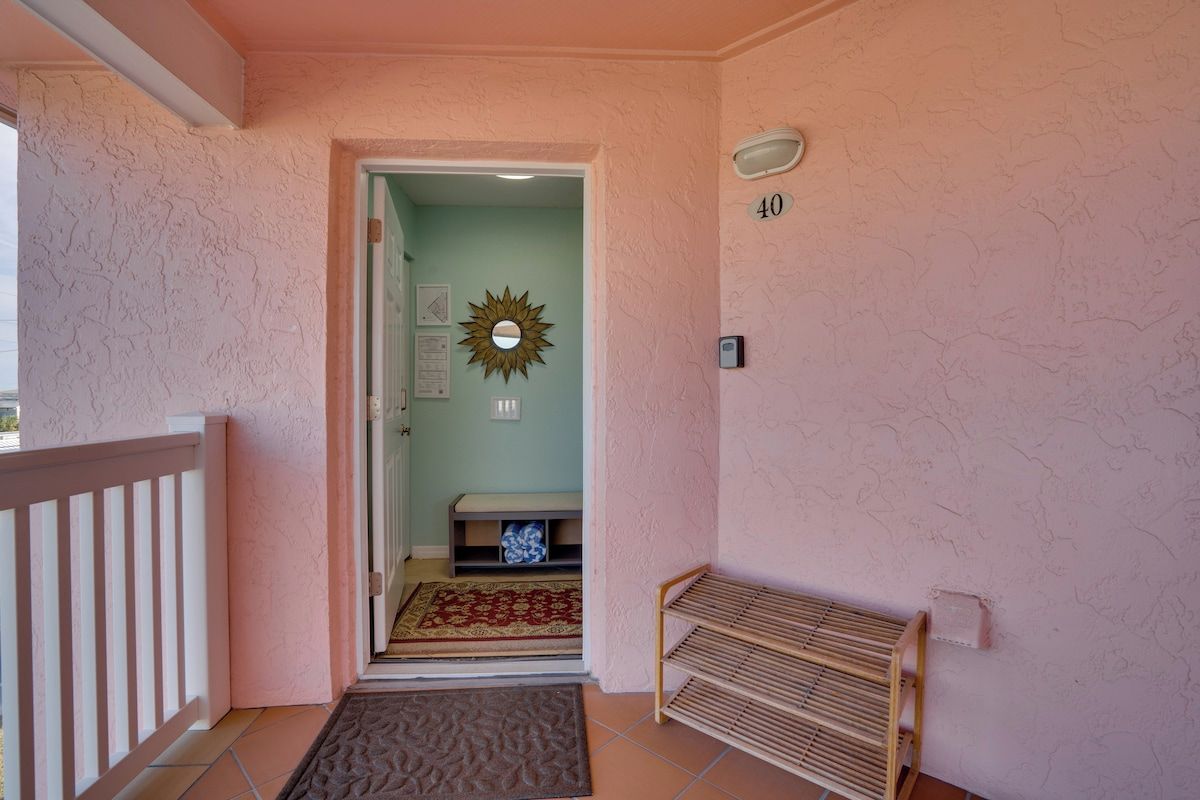 A hallway with a wooden bench, a door leading to a room, a number '40' on the wall, and a decorative sunburst mirror.